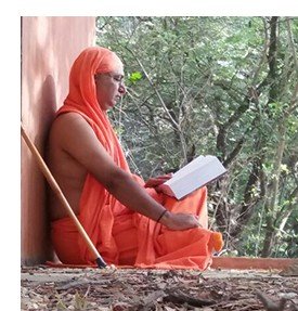 Swami Pradeeptananda Saraswati reading scripture outdoors at Aarsh Kutir